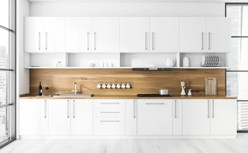 Kitchen with white cabinets, wood panel backsplash and white walls 