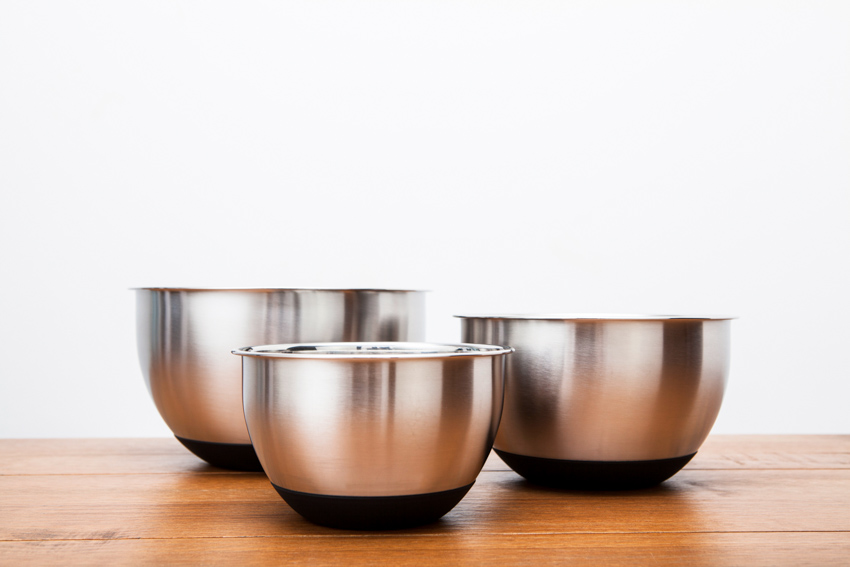 Three stainless steel bowls on top of a wood surface