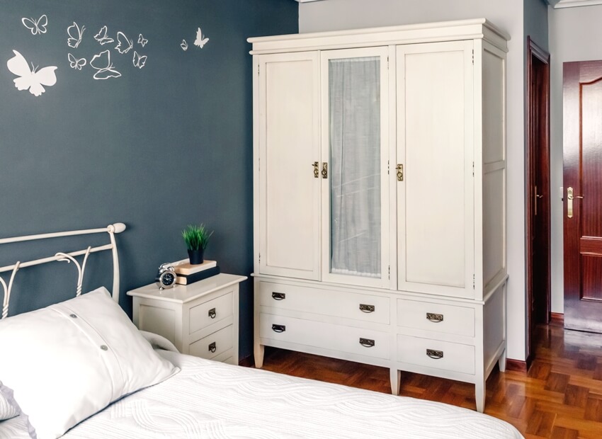 Bedroom with white bed, side table and armoire