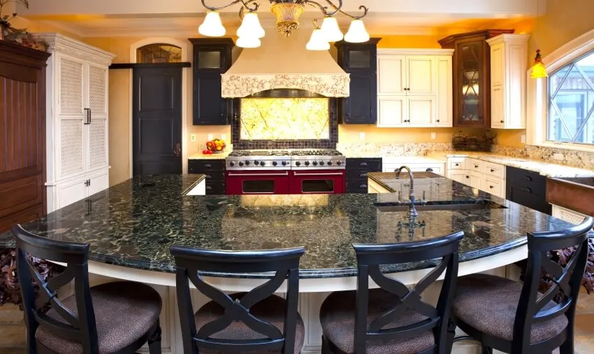U-shaped kitchen island with sink, chandelier, and antique brown granite countertops in kitchen
