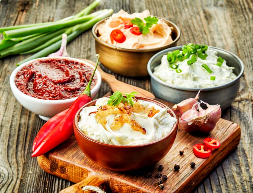 Various dip bowls on top of a wood table