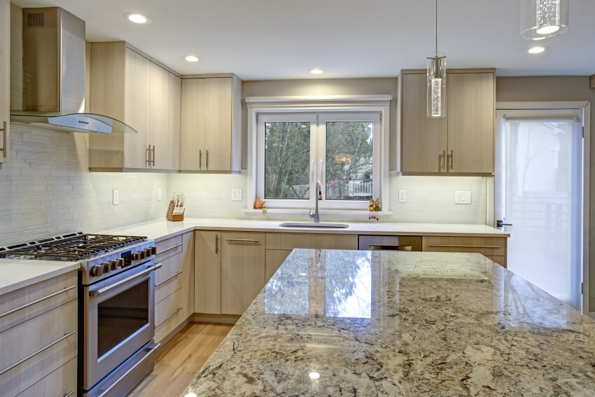 Well-lit kitchen with quartz countertop island, birch cabinets, and stylish pendant lights