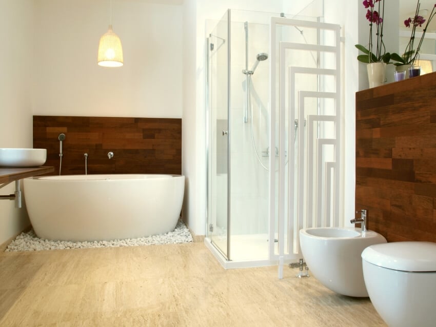 White bathroom with freestanding tub, wooden accent wall, and travertine floors