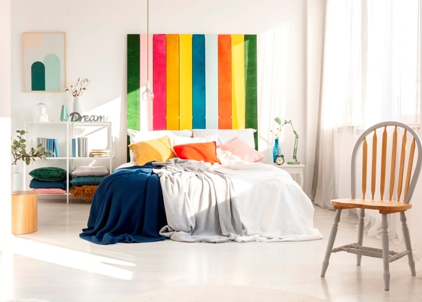 White bedroom with chair and rainbow colored bedhead