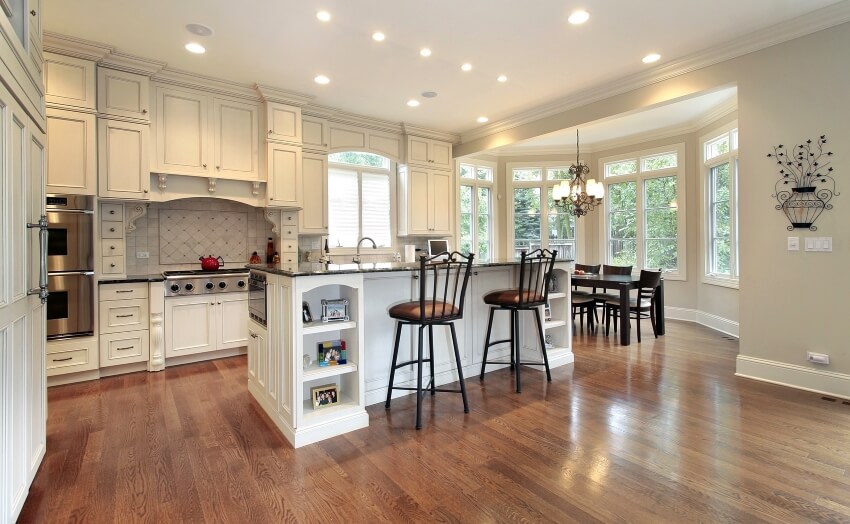 White cabinets and island hardwood floors in an open dining and kitchen with arts and crafts design