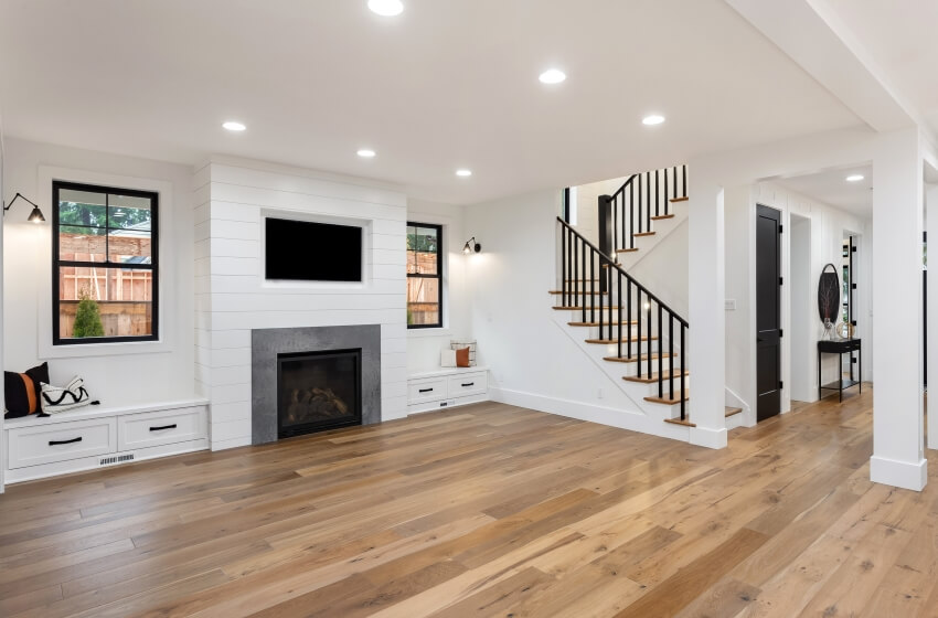 White farmhouse style living room features hardwood floors, nickel gap shiplap, and a fireplace