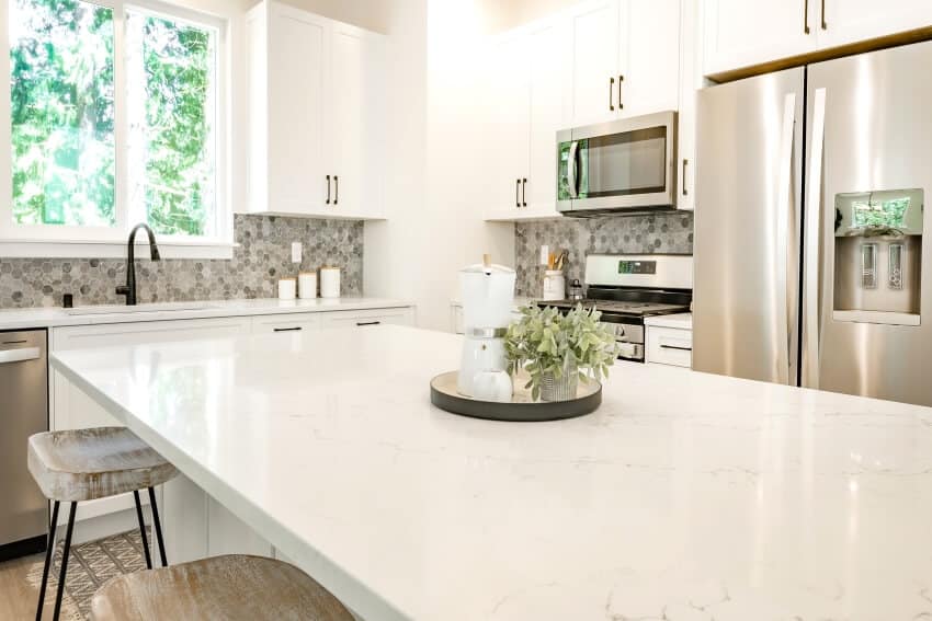 White kitchen with island, stools, marble countertops and penny tile backsplash