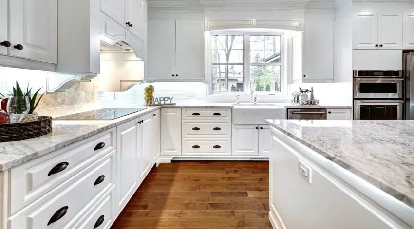 White kitchen with quartz countertops, cup pulls on cabinets, and hardwood floor