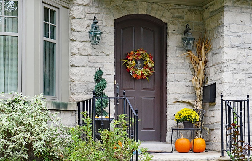House front entryway front door with wreath stone walling bay window porch lights