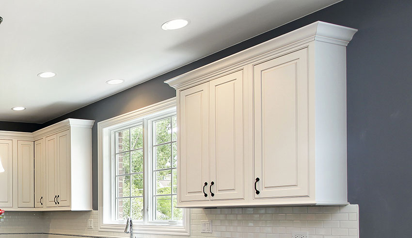 White kitchen cabinet with crown molding recessed lighting dark gray paint subway backsplash french window
