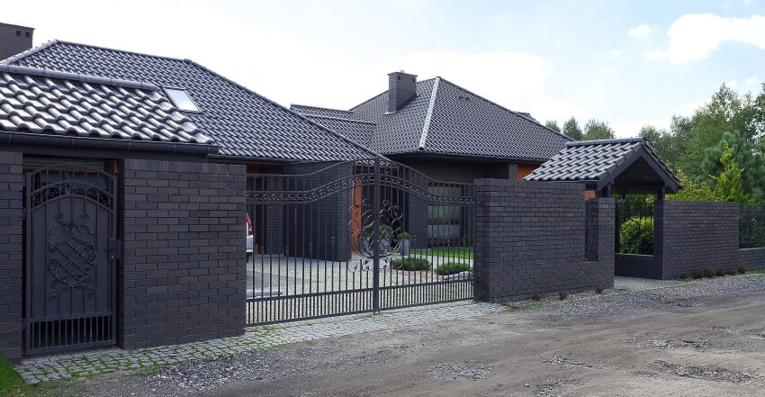 A black mansion with tile roof and brick walls