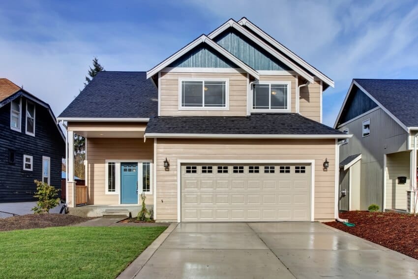 Beige painted house with blue door and cemented driveway