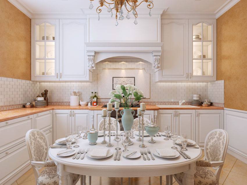 Kitchen with dark oatmeal walls, cabinets with galss fronts and round dining table with chairs