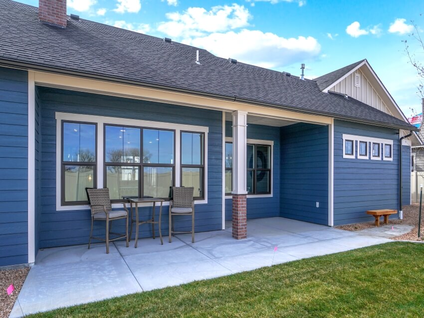 Back view of a dark blue house with two chairs and white pavers