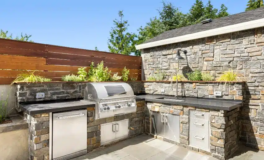 Backyard hardscape patio with outdoor barbecue and kitchen with gray slate backsplash