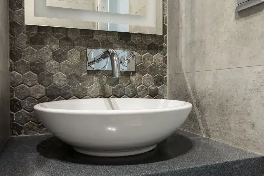 Bathroom with basin sink, hexagon tile backsplash, faucet, countertop, and mirror