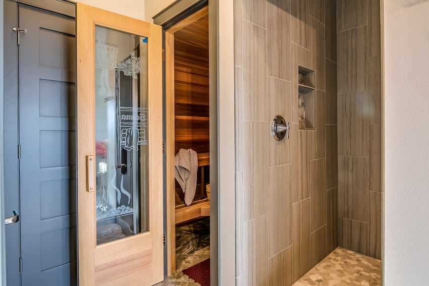 Bathroom with built-in sauna, shower door, and tile wall