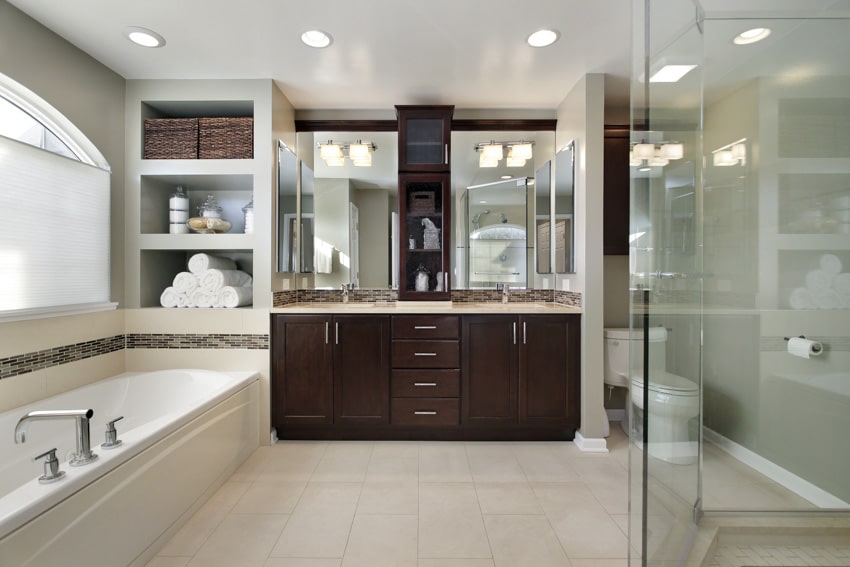 Bathroom with listello mosaic wall, tub, vanity area, cabinets, mirror, countertop, ceiling lights, and window
