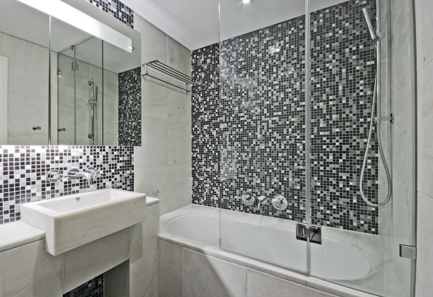 Bathroom with mosaic tile wall, sink, vanity mirror, and half glass shower door for bathtub