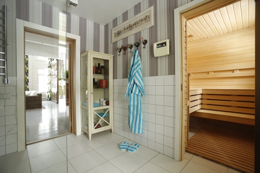 Bathroom with sauna, tile flooring, cabinet, and towel holder