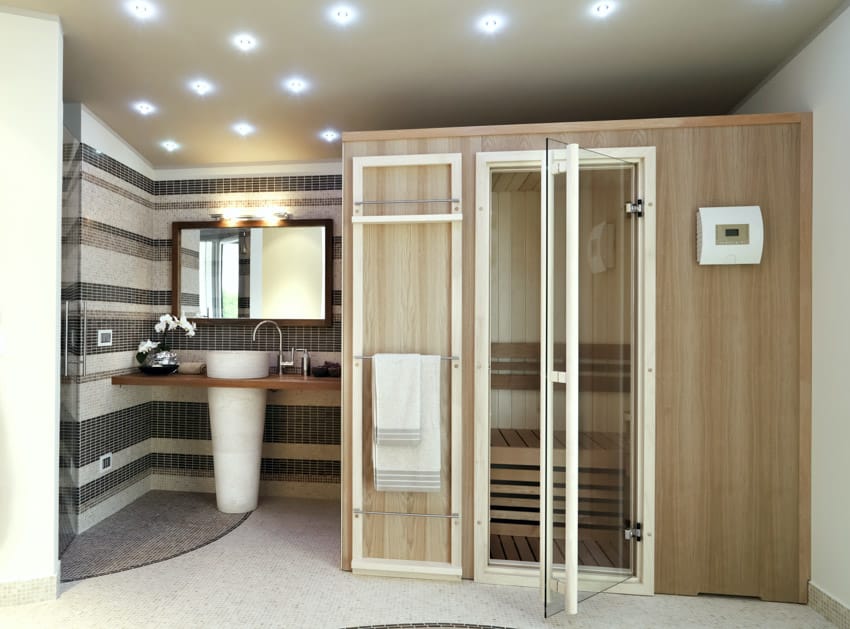 Bathroom with vanity area, mirror, sink, accent wall, ceiling lights, and sauna