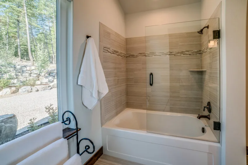 Bathroom with window, towel holder, and half glass shower door for bathtub