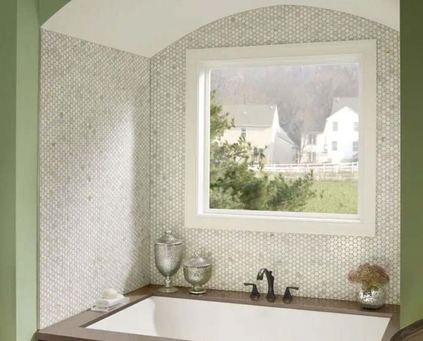 Bathroom with window, tub, and hexagon gold Calcatta backsplash