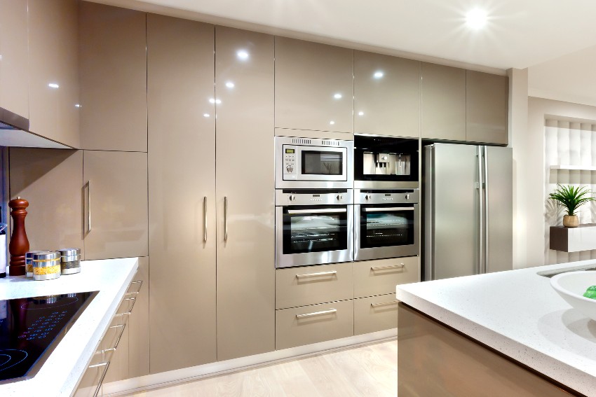 Beautiful kitchen interior with pvc cabintes and pantry cupboard fixed to the wall with stainless steels fridge and microwave oven