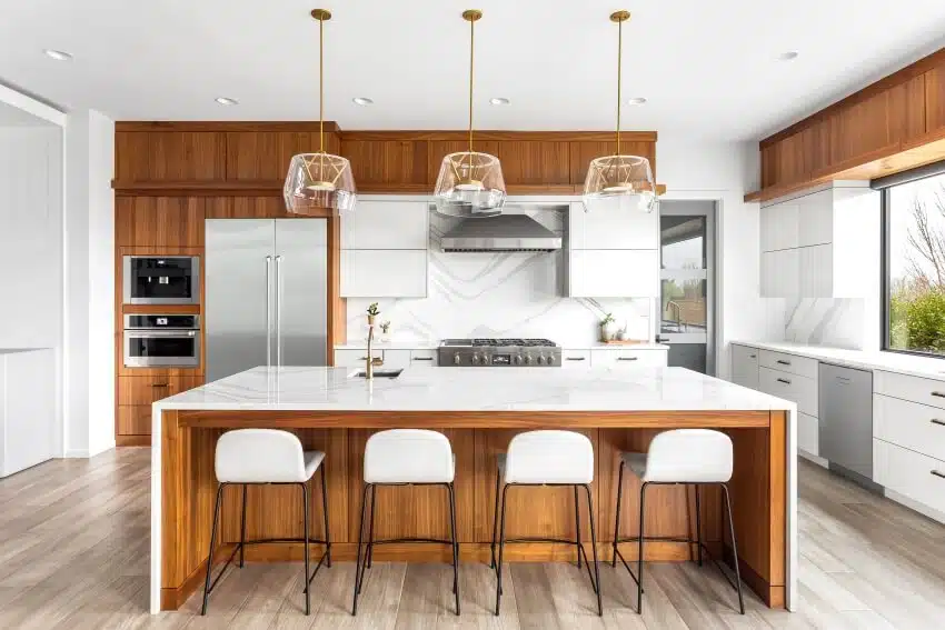 Beautiful kitchen with waterfall quartz island, pendant lights, and acacia wood cabinets