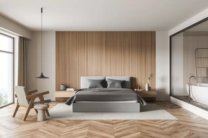 Room with gray bed, glass panel wall and herringbone wood floors