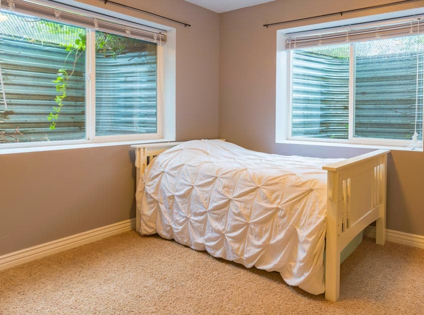 Bedroom basement with sliding windows, bed, comforter, and carpet floors