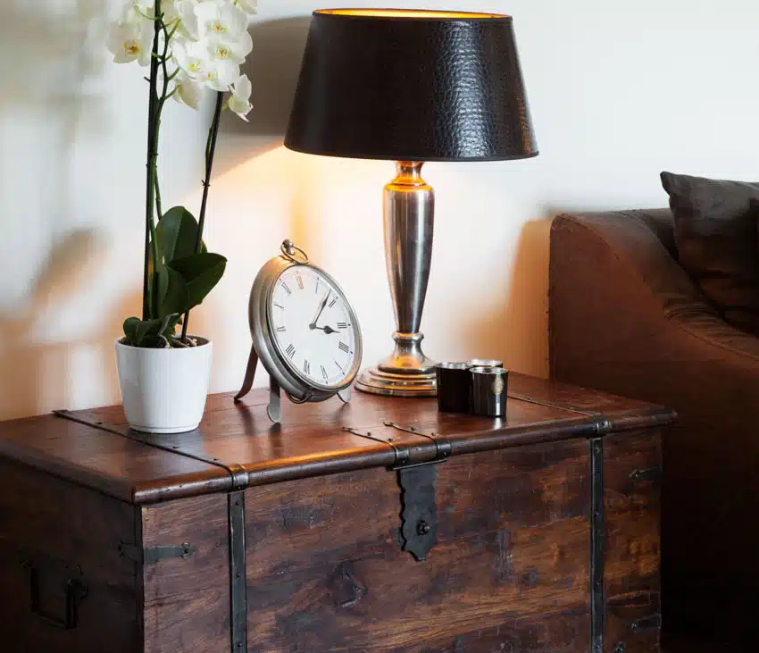Bedroom chest type of furniture with a lamp clock and plant on it