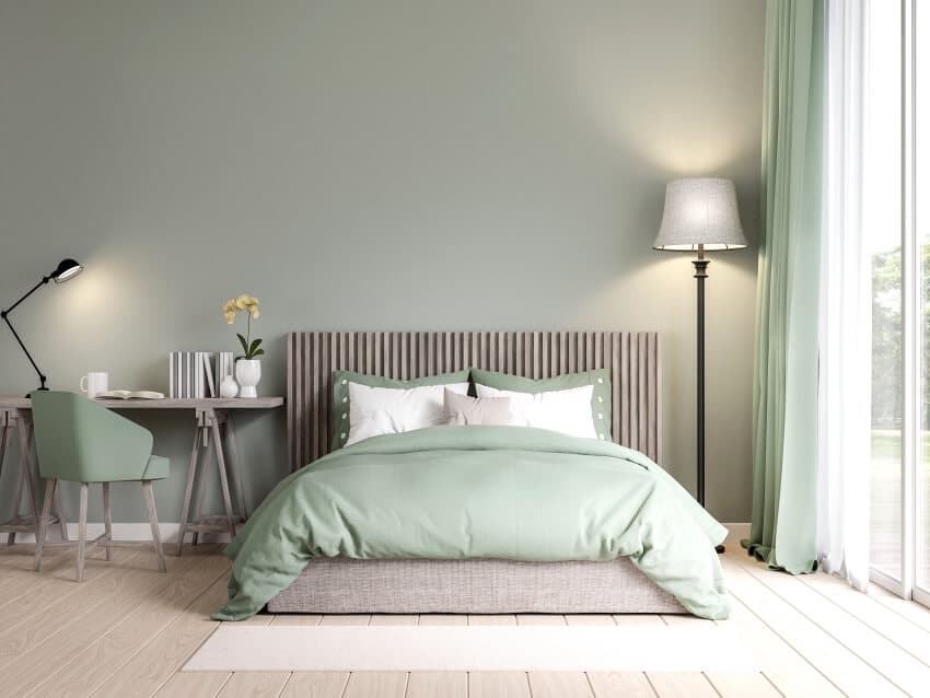 Bedroom in pastel green color with wooden floors, floor lamp, and panel wood headboard
