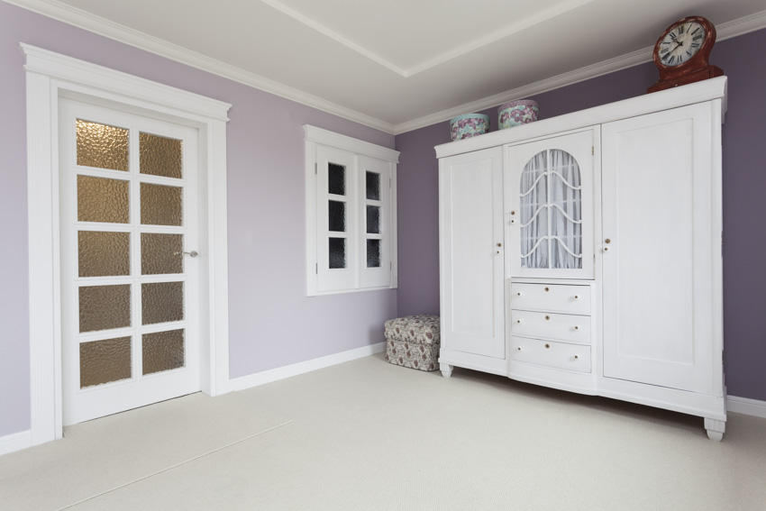 Bedroom with armoire, glass door, and lavender painted wall
