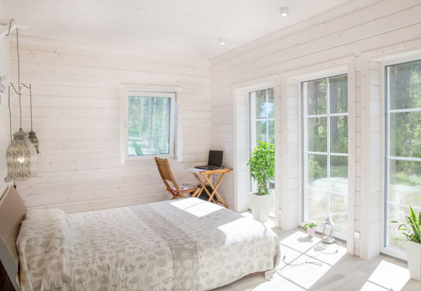 Bedroom with beadboard wall, glass door, windows, comforter, and ceiling lights