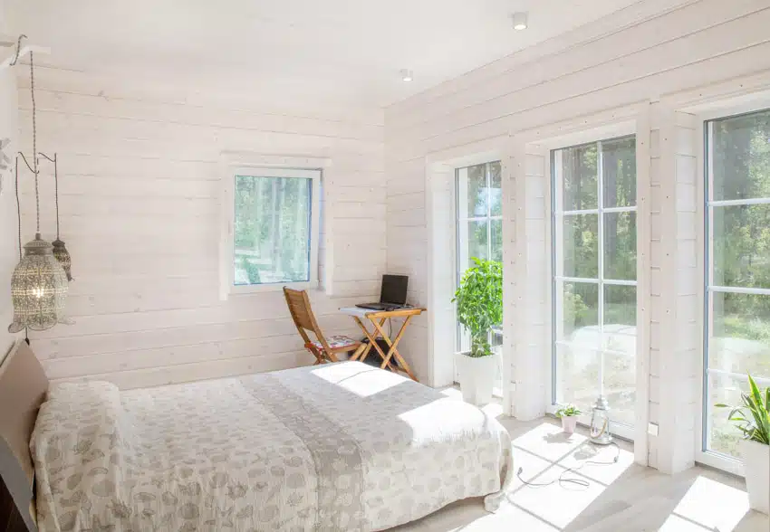 Bedroom with glass door, windows, comforter, and ceiling lights