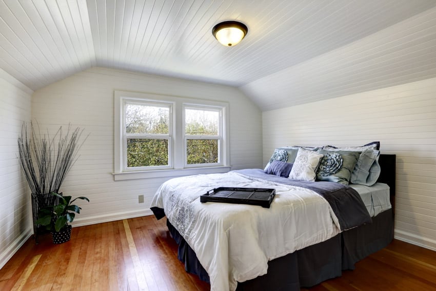 Bedroom with beadboard walls and ceiling, wood floors, flush mount light, and window