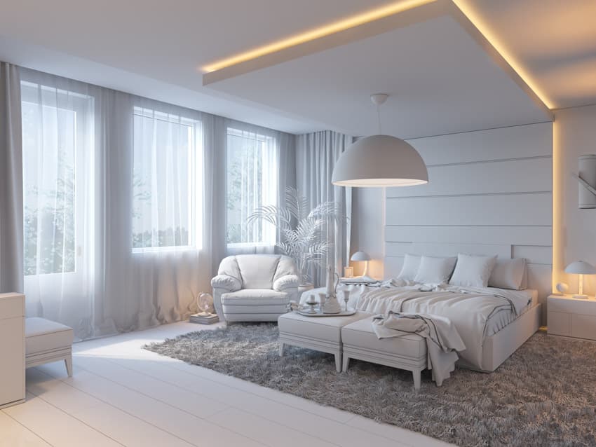 Bedroom with lighting fixtures, accent lights, white bedding, pillows, chair, windows, and curtains
