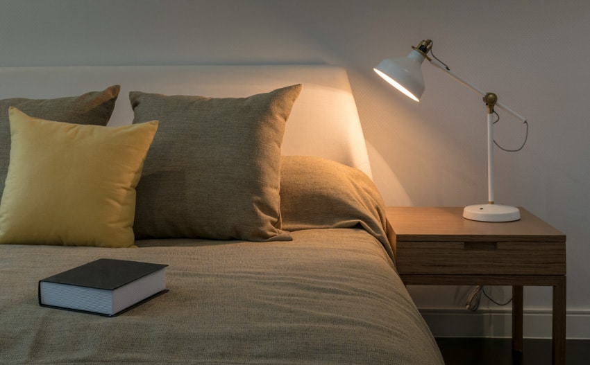 Bedroom with a table lamp on a nightstand and book on bed