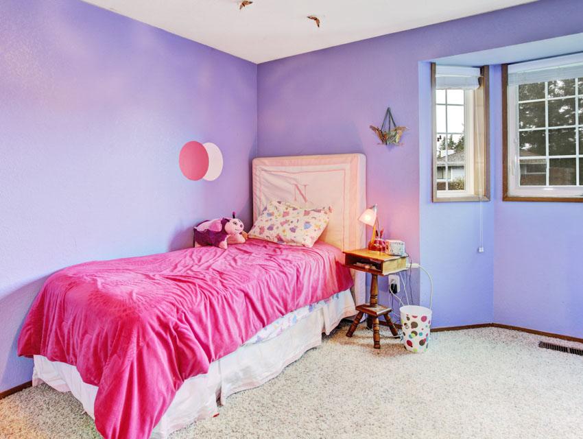 Bedroom with pink bedding, headboard, pillow, bay window, nightstand, and lavender painted wall