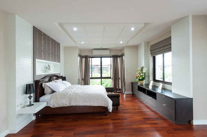 Bedroom with recessed lights, wood flooring, console table, windows and taupe curtains