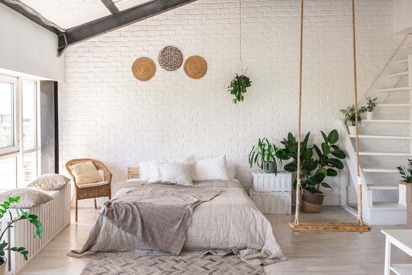 Bedroom with romantic light colors, pillows, indoor plants, chair, and window