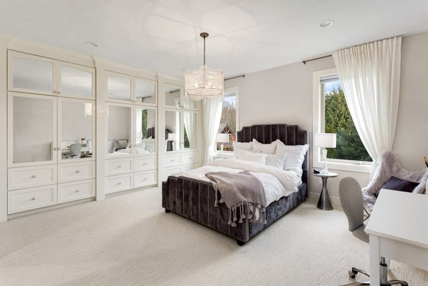 Bedroom with white walls, chandelier, pillows, headboard, desk, and chair