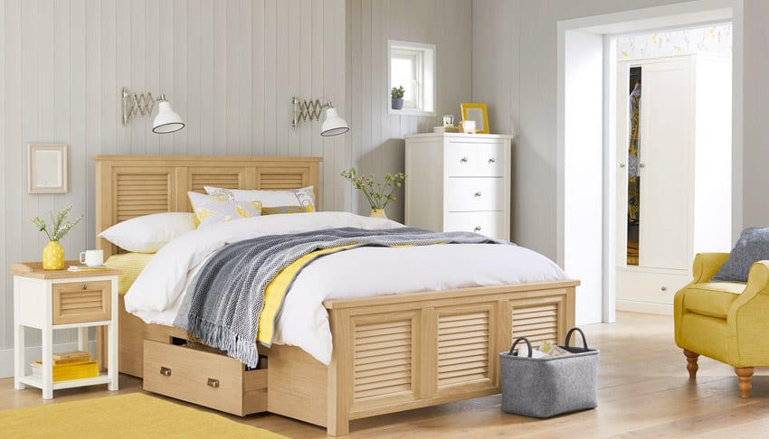 Bedroom with wood bed frame, bedding, pillows, lighting fixtures, nightstand, small closet, and yellow chair