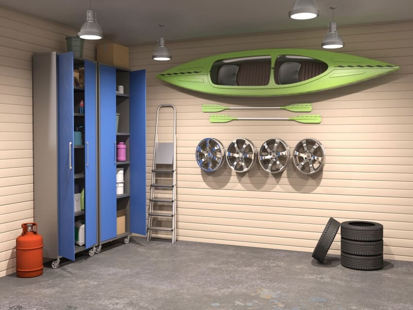 Big garage interior with green kayak hung with utility hooks, standing cabinet, and pendant lights