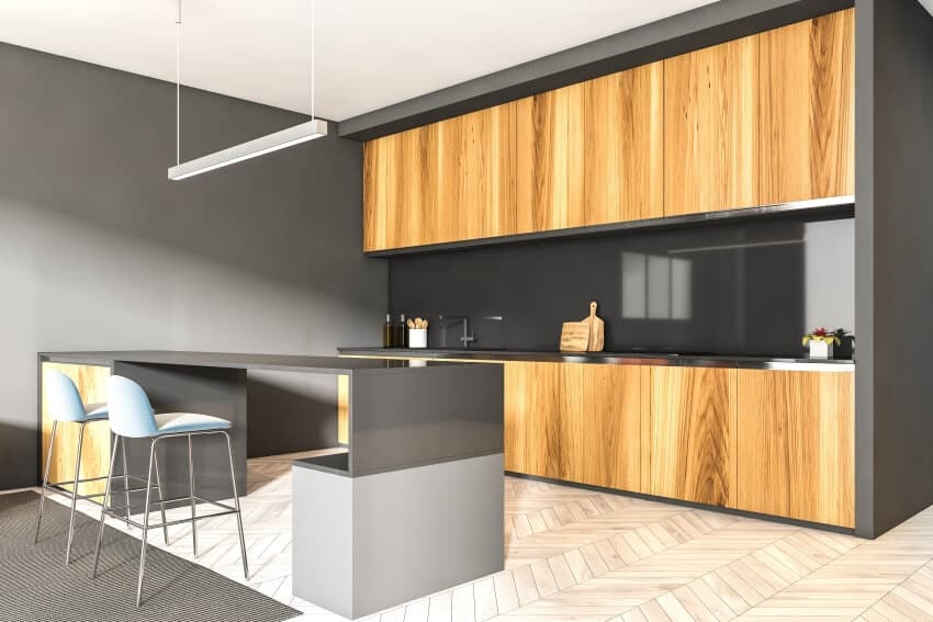 Black and wood modern kitchen with chevron parquet floor, and breakfast counter with chairs