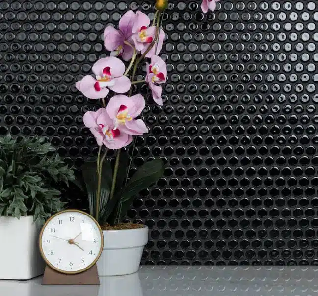 Black tile backsplash with potted orchid and alarm clock