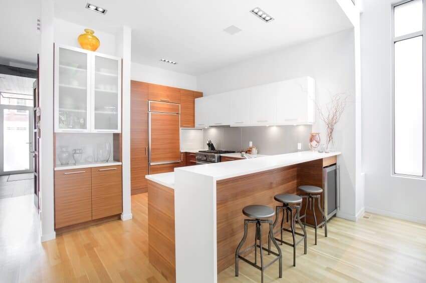 Bright modern kitchen with wood paneling cabinets and floors, and an island and three bar stools