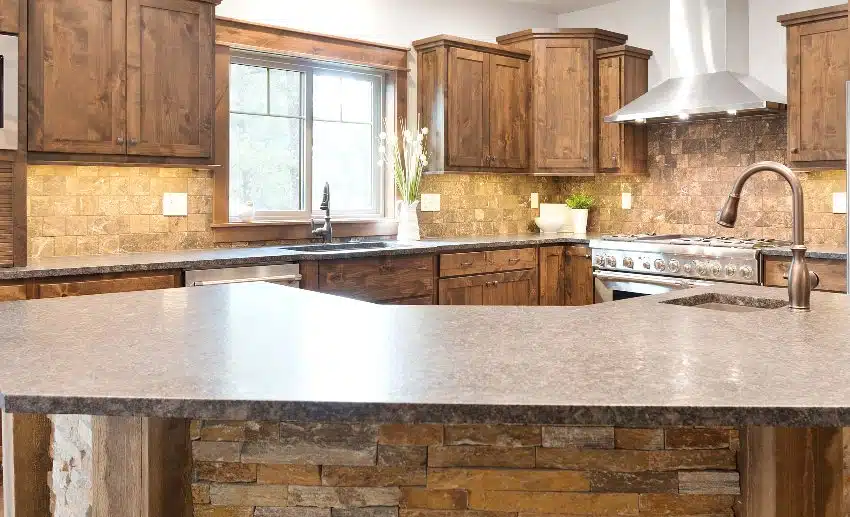 Brown kitchen with wood cabinets, slate backsplash, and island with faucet