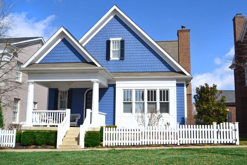 House with curb appeal colors, siding, chimney, picket fence, and hedges